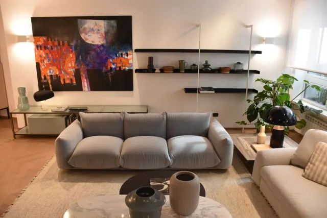 Un salotto dello showroom di Milano, con divano, quadro e librerie.