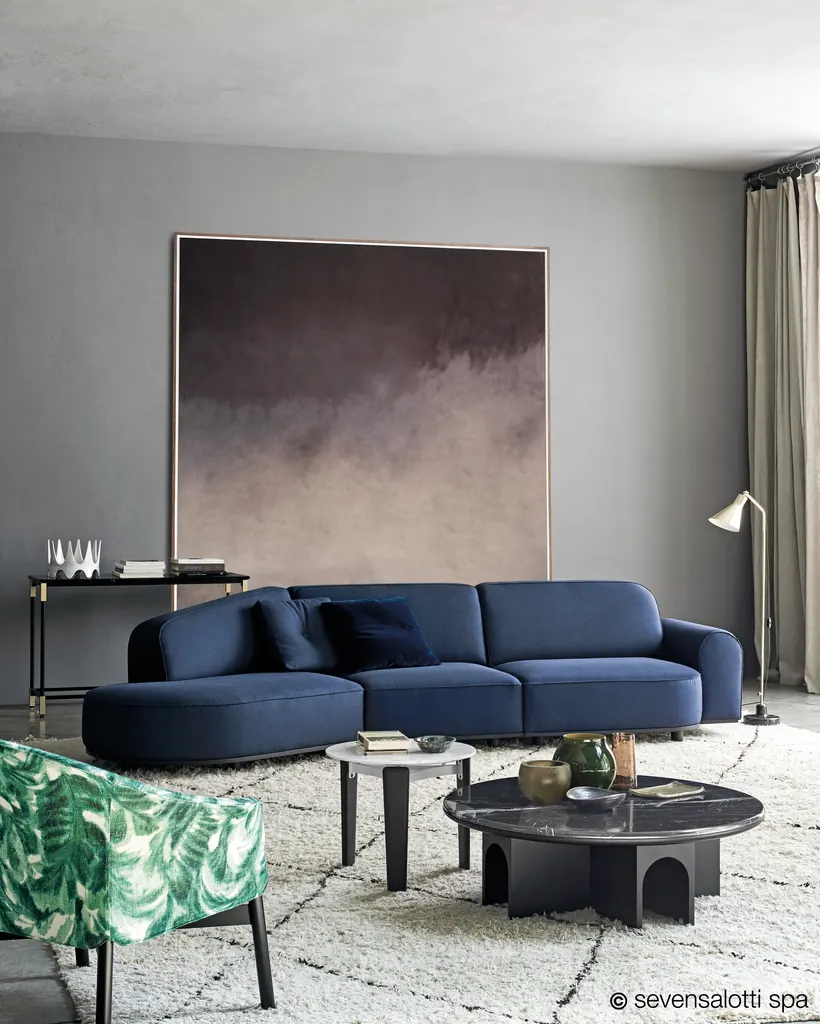 Divano Arcolor Arflex blu con cuscini scuri in un soggiorno con un grande quadro e un tappeto chiaro
