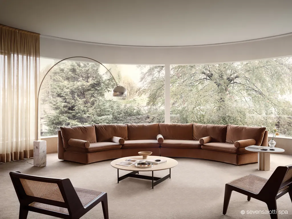 Large tan Arflex Ben Ben curved sofa in a circular room with windows onto the garden