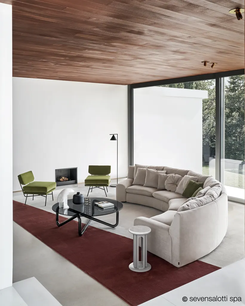 Light grey Arflex Ben Ben curved sofa with cushions, a wooden ceiling and a red rug