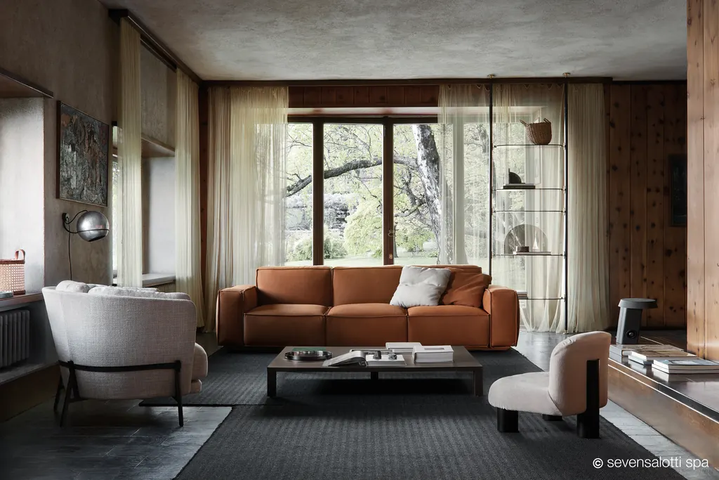 Poltrona Botolo Arflex bassa in tessuto chiaro in un soggiorno con pareti in legno e divano color cuoio