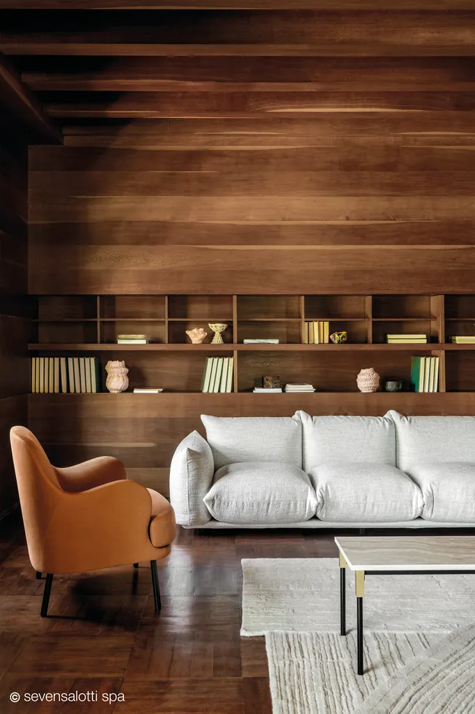 Poltrona Brigitte Arflex color cuoio vista di lato, davanti a un divano bianco e a una libreria in legno