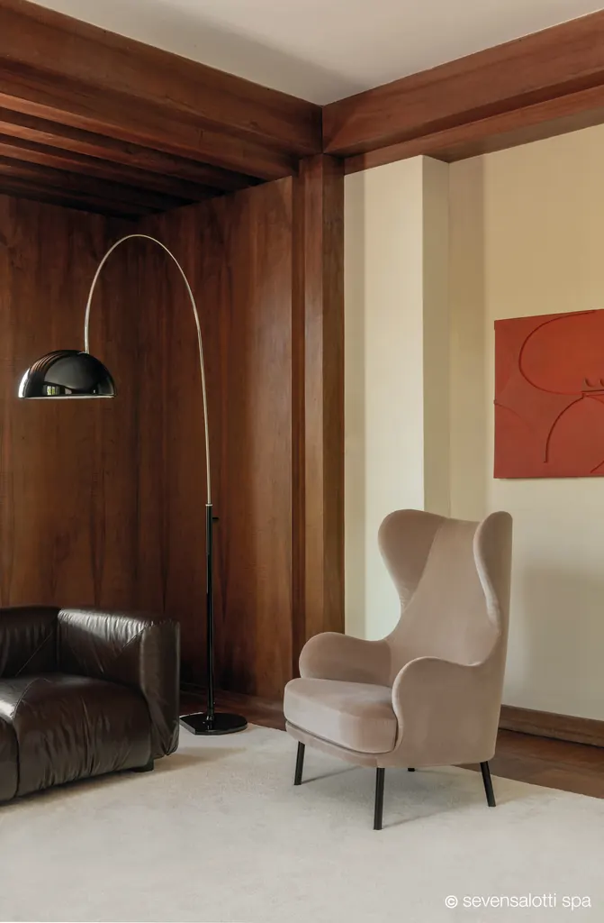 Poltrona Brigitte bergère Arflex color tortora accanto a una lampada ad arco