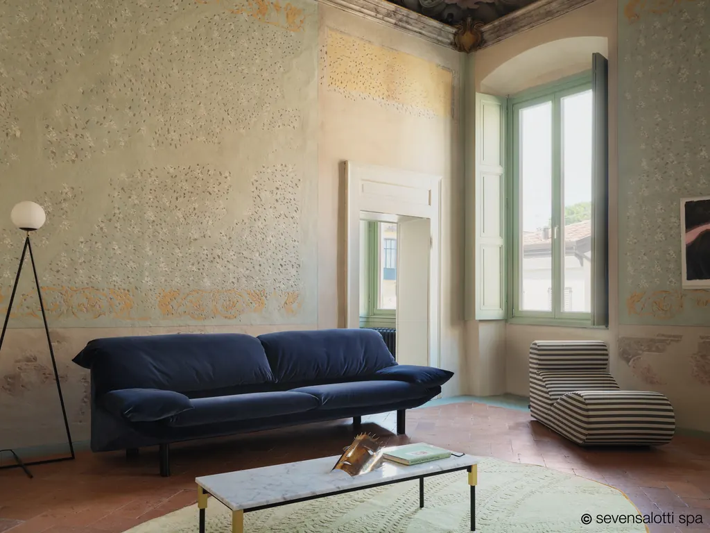 Divano Casablanca Arflex blu in una sala con pareti decorate, pavimento in cotto e tavolino in marmo