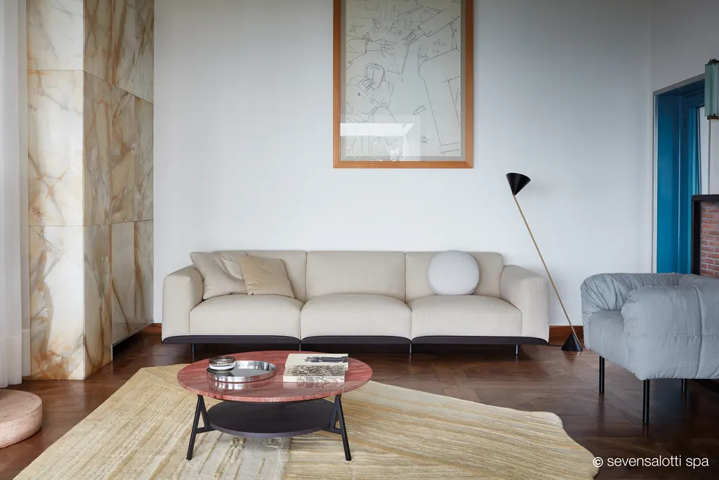 Divano Claudine Arflex color crema in un soggiorno con parquet, quadro e parete in pietra venata