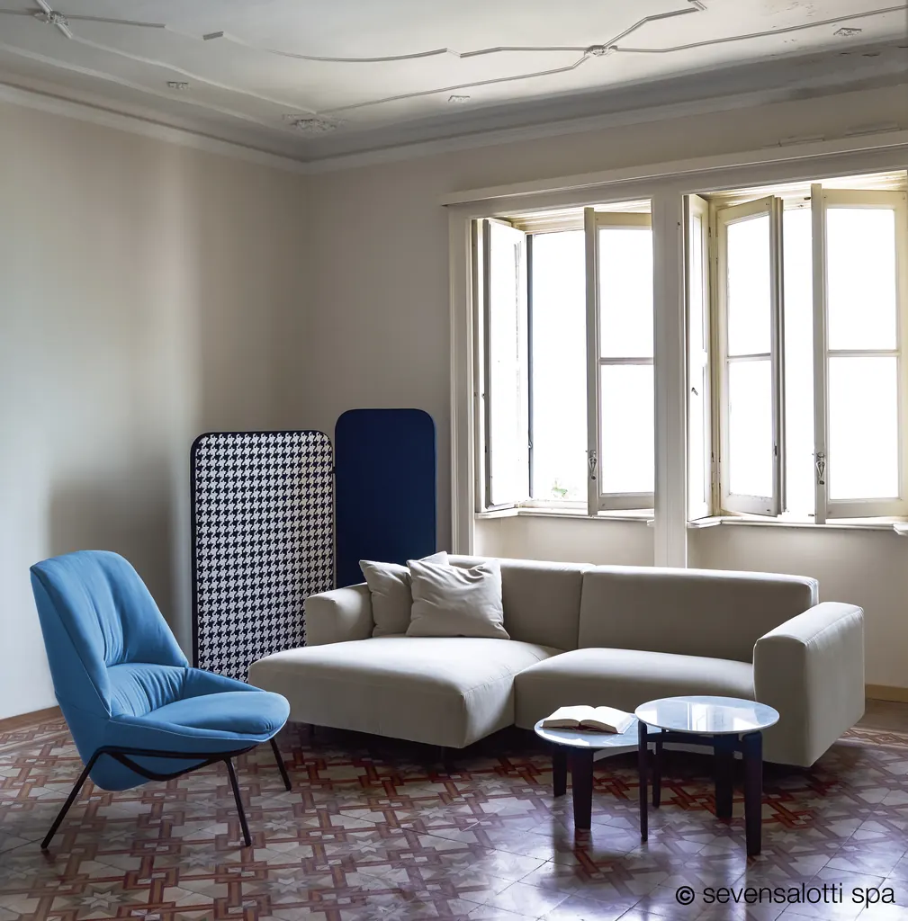 Divano Claudine Arflex grigio chiaro con chaise longue accanto a una poltrona blu e a due finestre