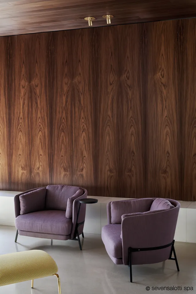 Due poltrone Cradle Arflex color malva davanti a una parete in legno