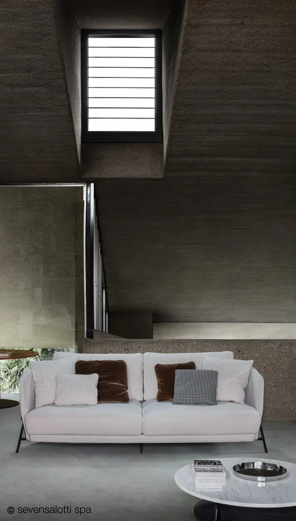 Light grey Arflex Deep Cradle sofa with brown and grey cushions in a space with concrete walls and a skylight