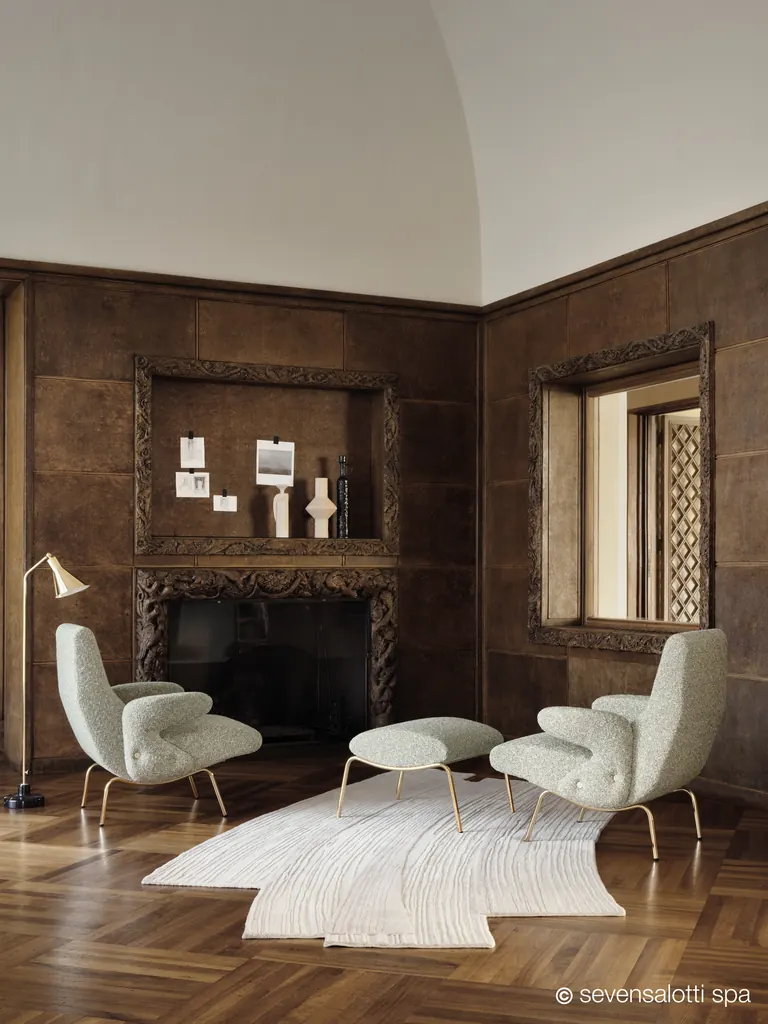 Due poltrone Delfino Arflex chiare con pouf in una sala rivestita in legno scuro con camino