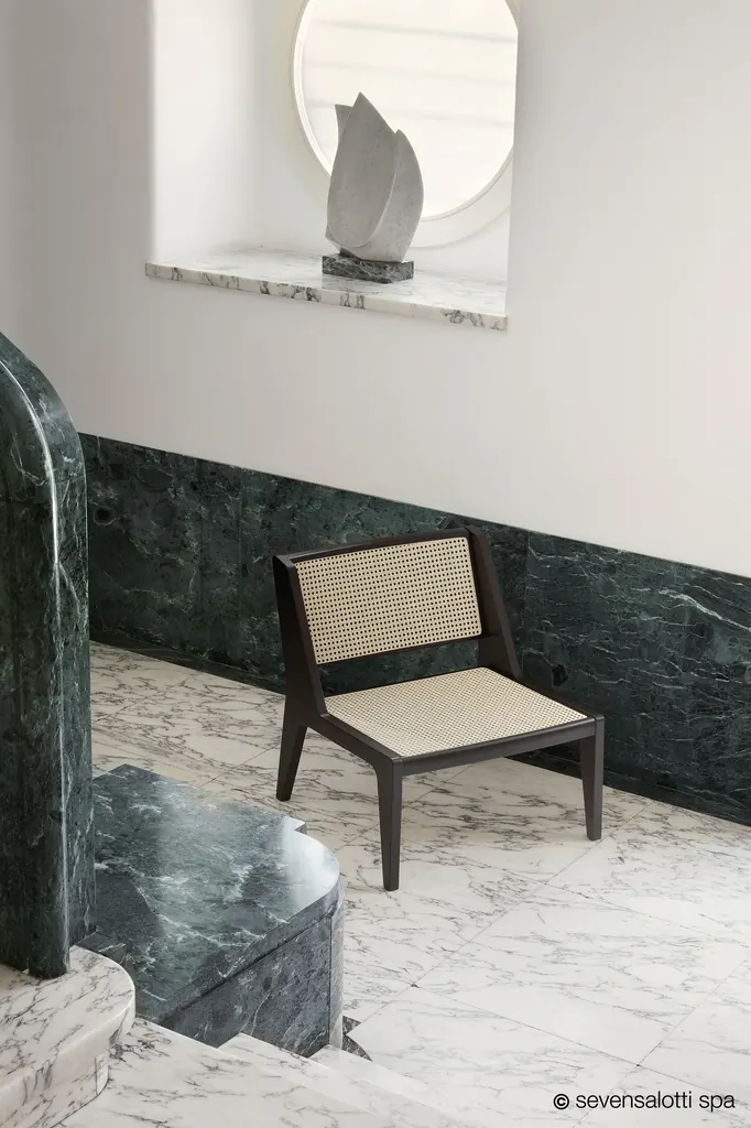 Poltrona Delta Vienna Arflex su un pavimento in marmo bianco, davanti a una boiserie in marmo verde