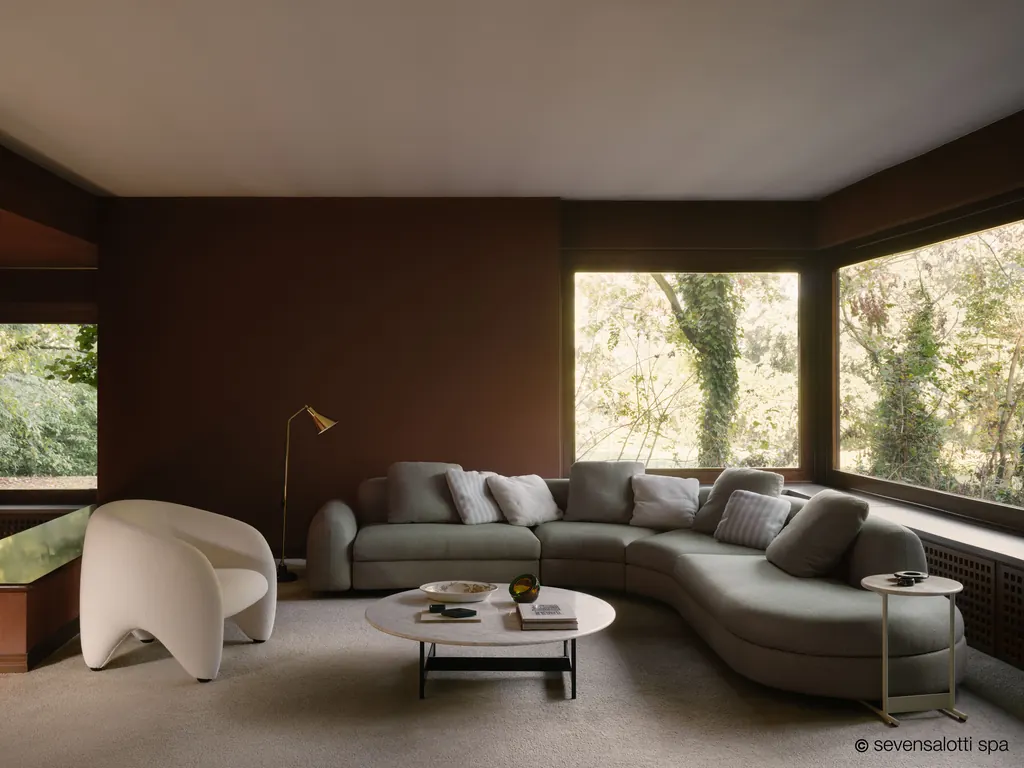 Composizione curva Edo Arflex verde salvia in una sala con finestre d'angolo sul giardino