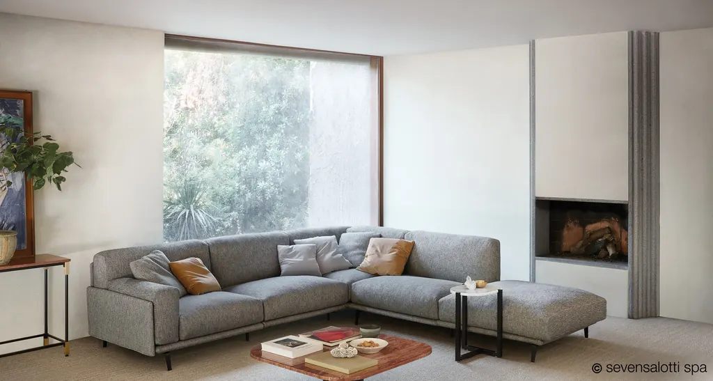 Composizione angolare Frame Arflex grigia con cuscini in un soggiorno con grande finestra e camino