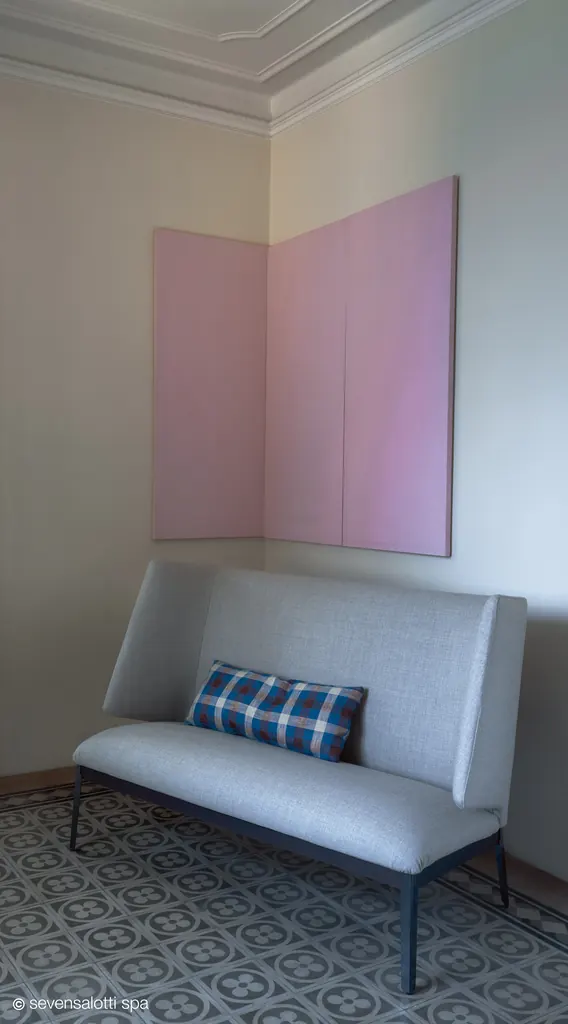 Love seat Hug Arflex grigio chiaro con cuscino a quadri, in un angolo con pannello rosa