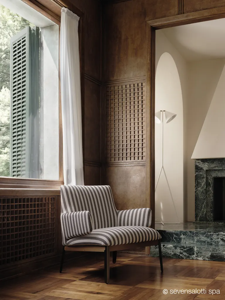 Poltrona Hug Arflex a righe in un interno rivestito in legno, accanto alla finestra