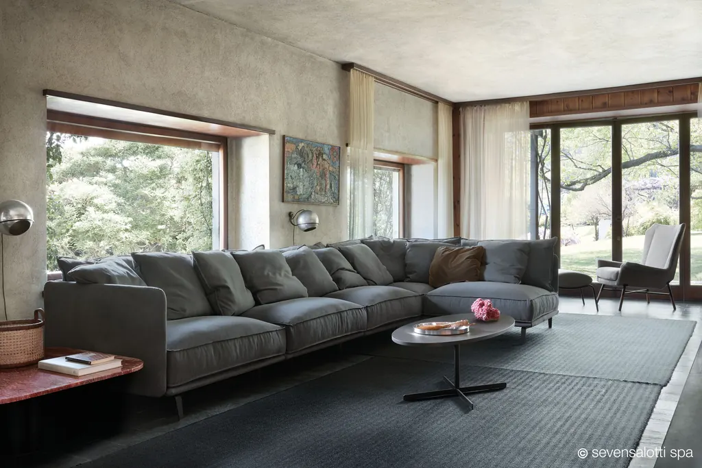Large grey Arflex K2 corner composition with many cushions in a living room with glass walls onto a garden
