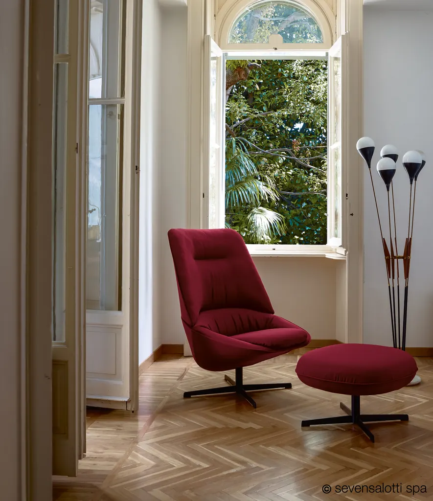 Poltrona Ladle Arflex rossa girevole con pouf davanti a una finestra aperta sul giardino
