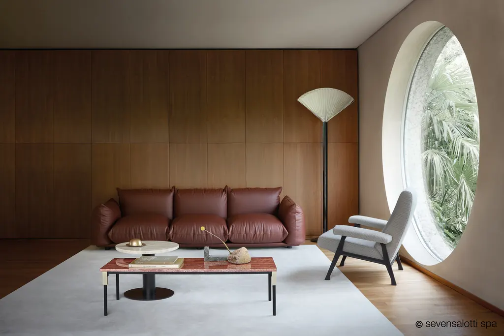 Brown Marenco Arflex sofa in a wood-clad living room with a circular window