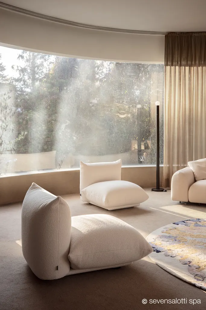 Cream Marenco Arflex armchairs in front of a curved window