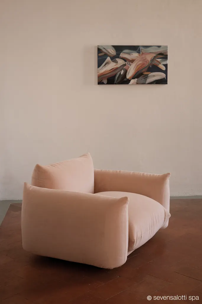 Poltrona Marenco Arflex rosa su un pavimento in legno scuro, con un quadro alla parete
