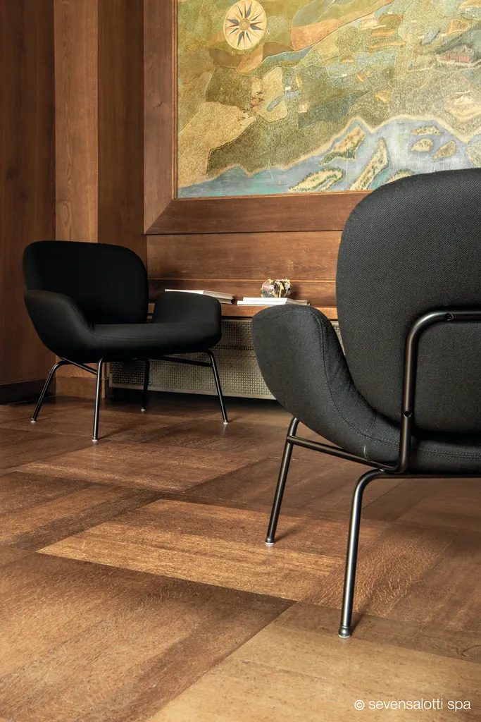 Poltrone Momo Arflex nere in un ambiente con pareti in legno e una grande mappa dipinta
