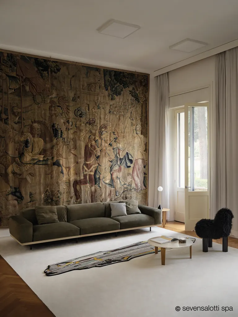 Divano Naviglio Arflex verde scuro in una sala con grande arazzo e finestra