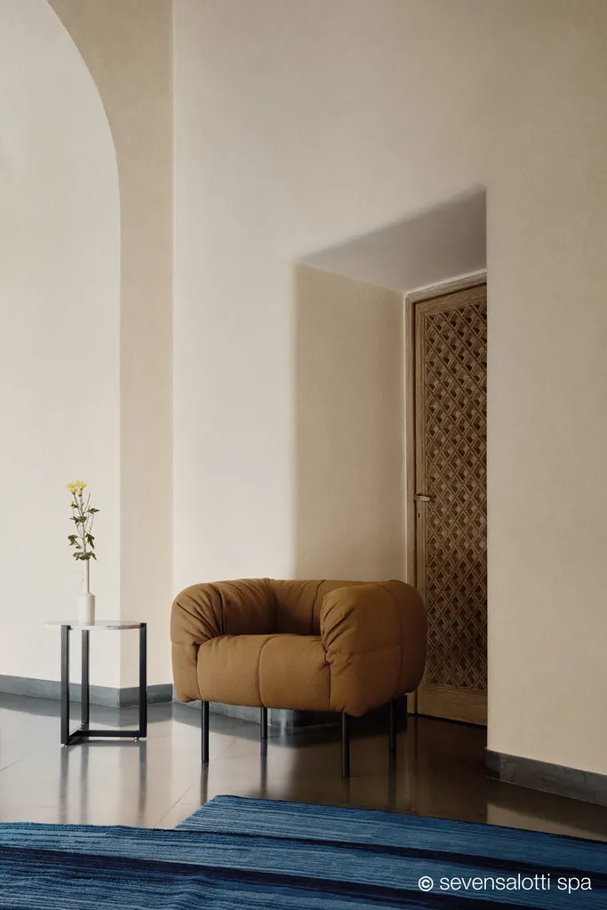Poltrona Pecorelle Arflex color cuoio in un ingresso con arco e porta a grata
