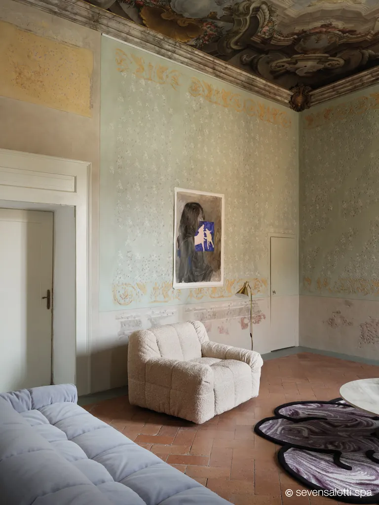 Poltrona Strips 77 Arflex bianca e divano azzurro in una sala affrescata con parquet