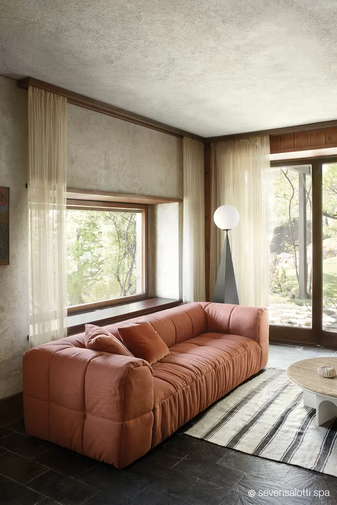 Terracotta Arflex Strips sofa in front of a large window