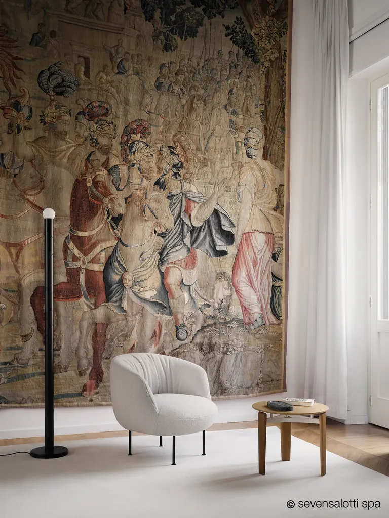 Poltrona Supplì Arflex bianca davanti a un grande arazzo antico, con lampada da terra e tavolino in legno