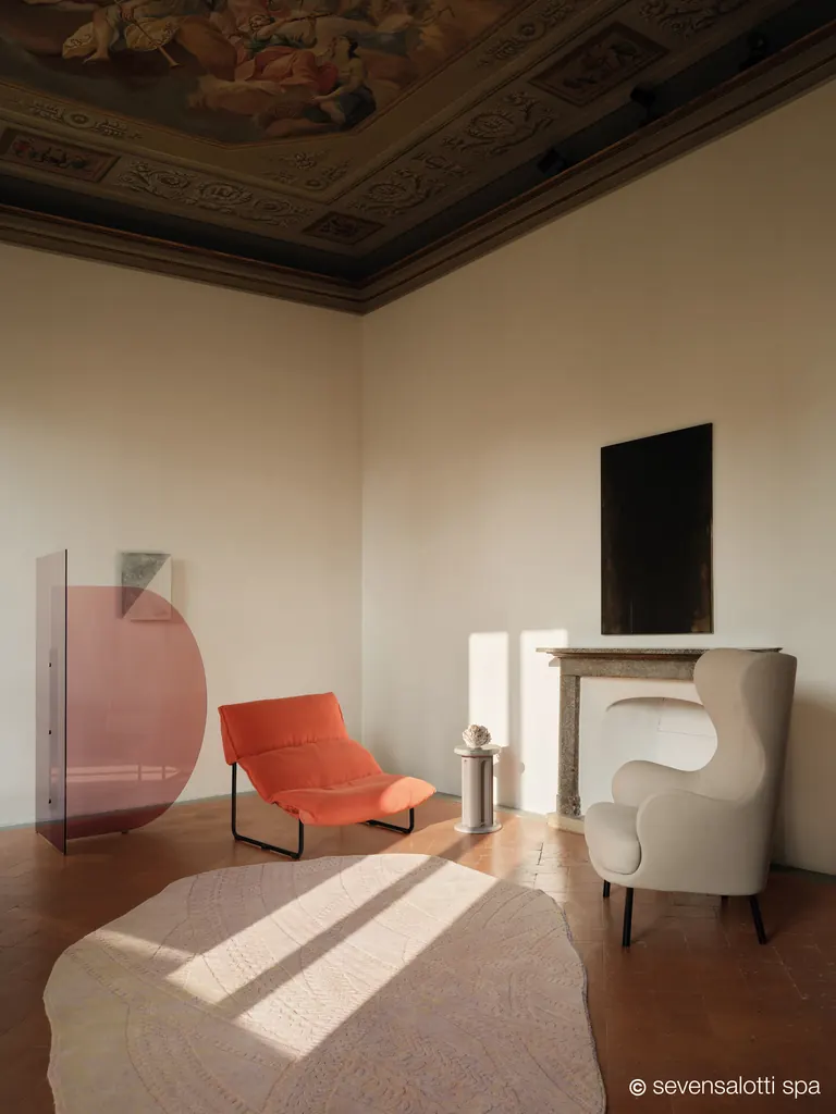 Poltrona Taboga Arflex arancione in una sala con soffitto affrescato e camino