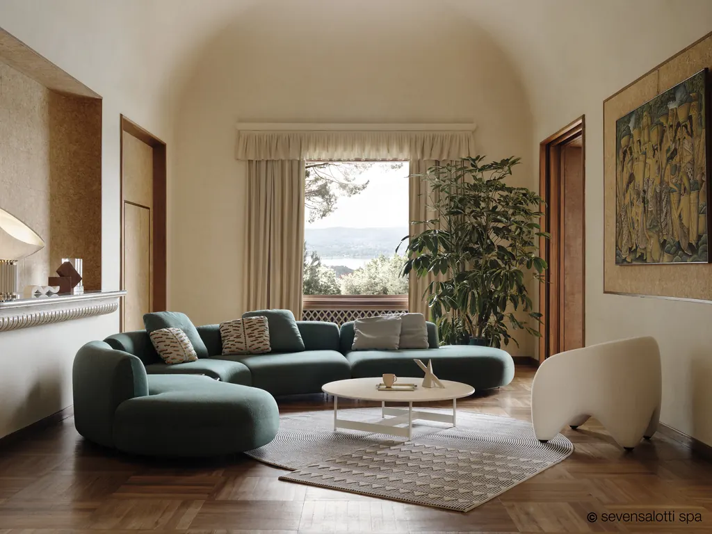 Divano curvo Tokio Arflex verde scuro in una sala con finestra ad arco e parquet