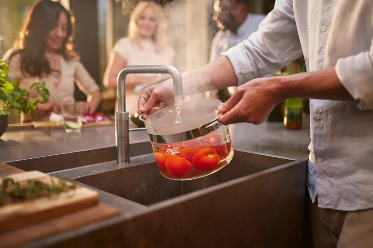 Pomodori sbollentati con l'acqua bollente di un rubinetto Quooker in una cucina