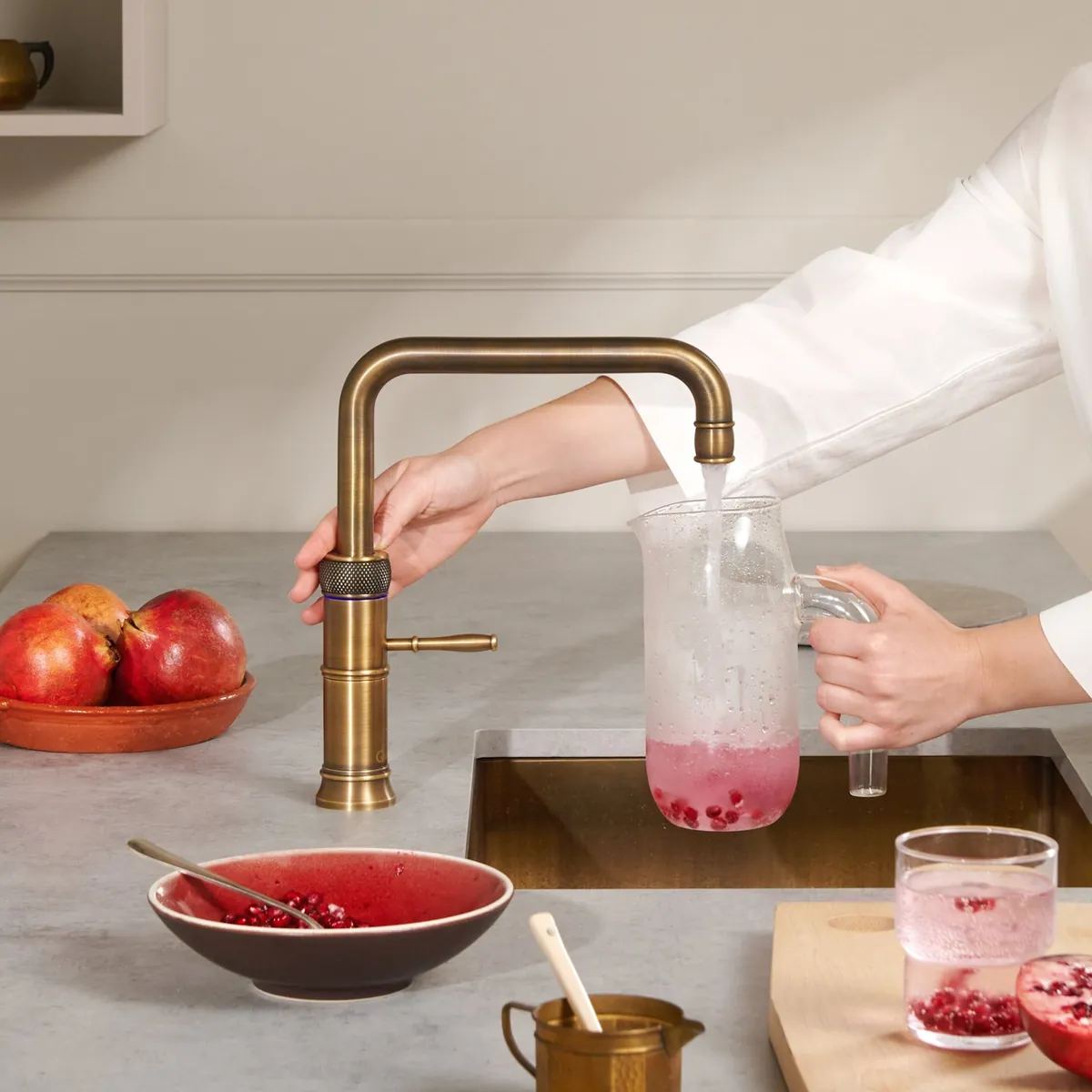Rubinetto Quooker Classic Fusion Square in ottone patinato mentre riempie una caraffa