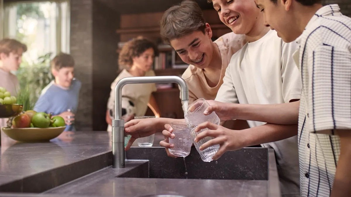Ragazzi che riempiono bottiglie di acqua frizzante da un rubinetto Quooker con CUBE