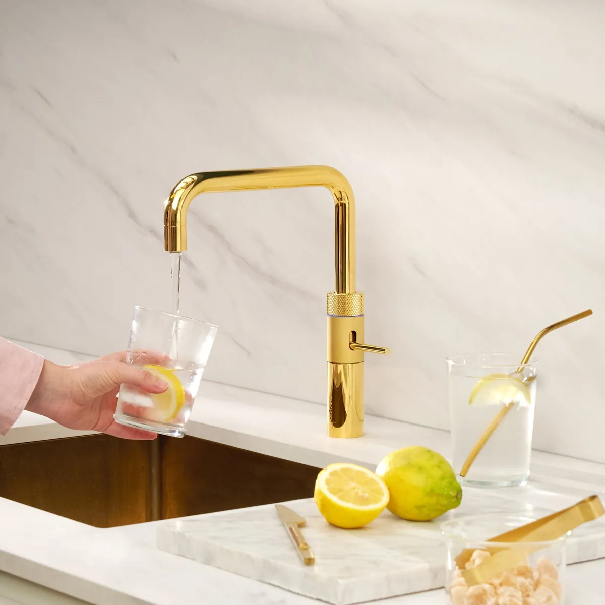 Rubinetto Quooker Fusion Square oro con acqua filtrata in un bicchiere