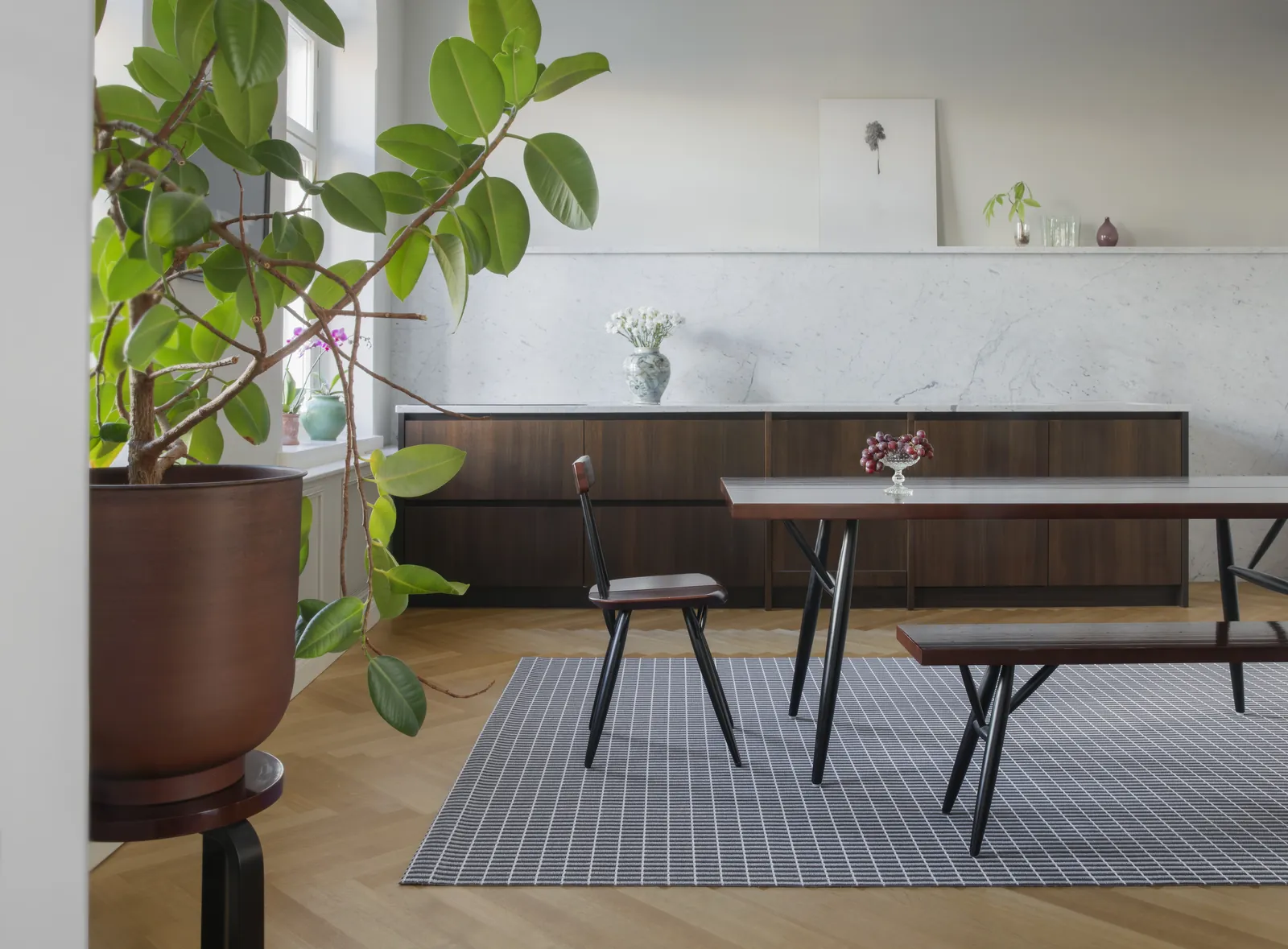 Tappeto Woodnotes Esplanadi in filato di carta sotto un tavolo da pranzo, in una sala luminosa con piante