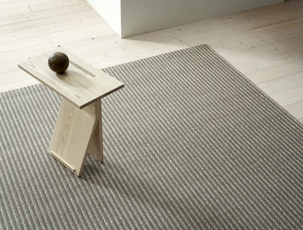 Tappeto Woodnotes Field color nutria e pietra con un tavolino in legno