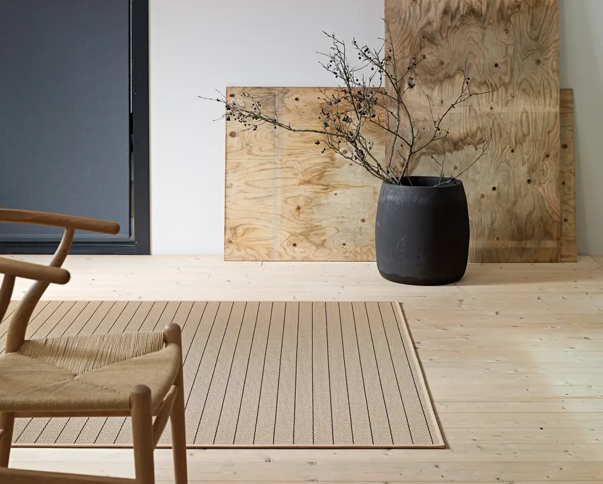 Tappeto Woodnotes Line naturale e nero su un parquet chiaro