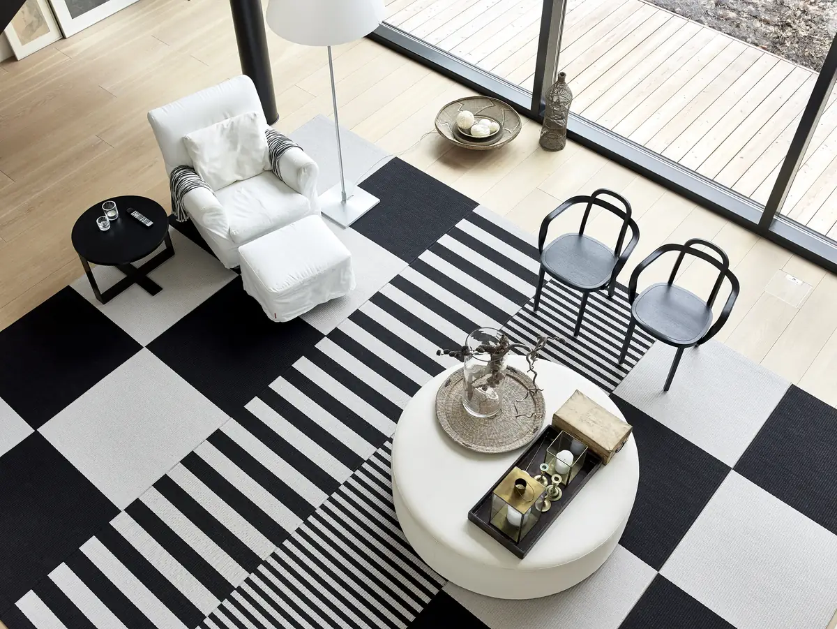 Tappeti Woodnotes Squareplay e Big Stripe bianchi e neri in un soggiorno visto dall'alto