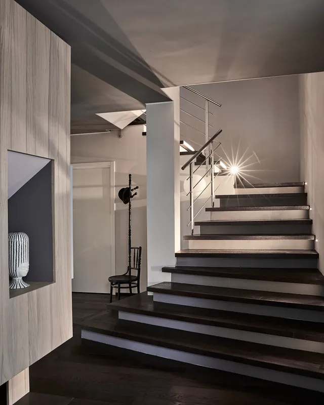 Ingresso con scala e parete rivestita in legno con nicchia